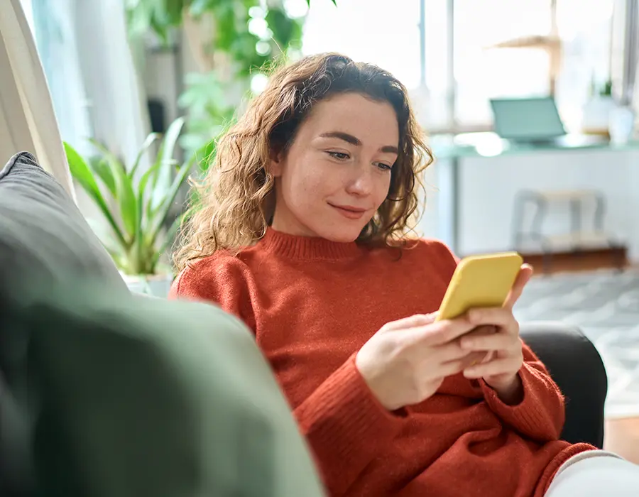 woman sitting on couch holding phone